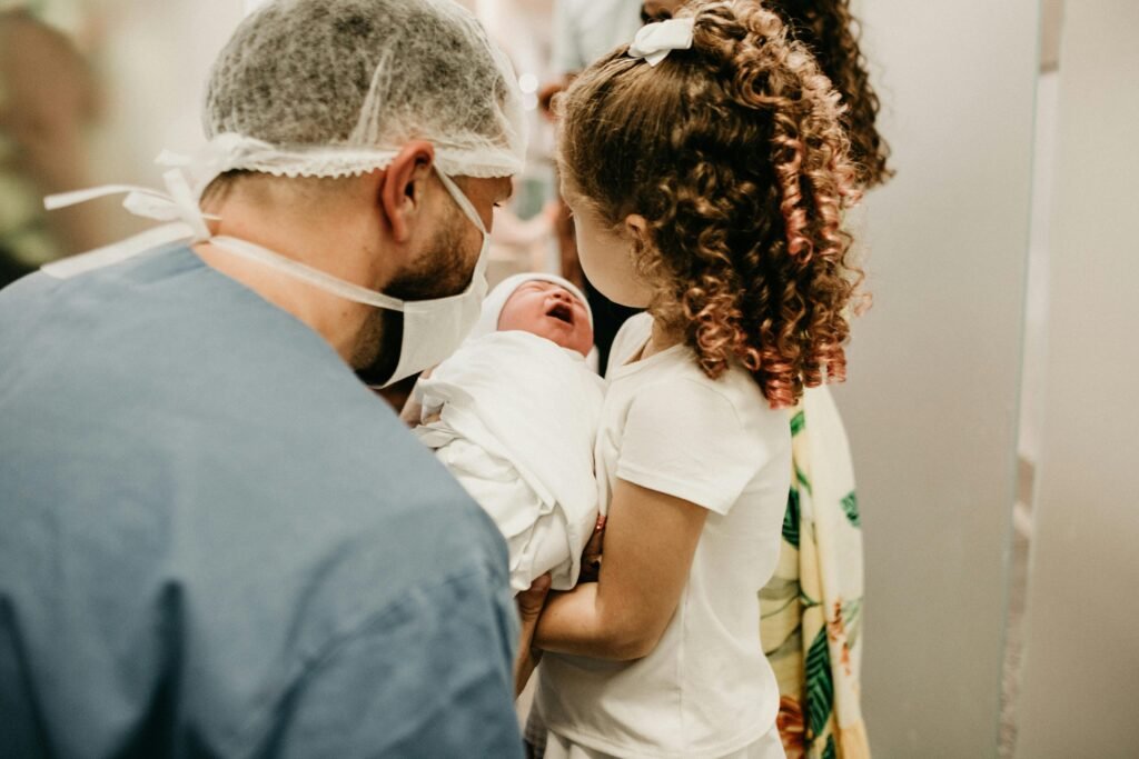 A happy family moment as a young girl meets her newborn sibling in the hospital.