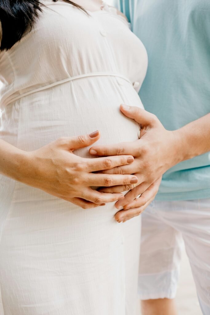 Close-up of hands gently embracing a baby bump in a warm, serene setting.